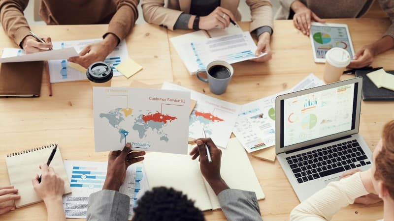 Diverse professionals brainstorming with laptops and charts in a contemporary office setting., tags: heatmaps - pexel