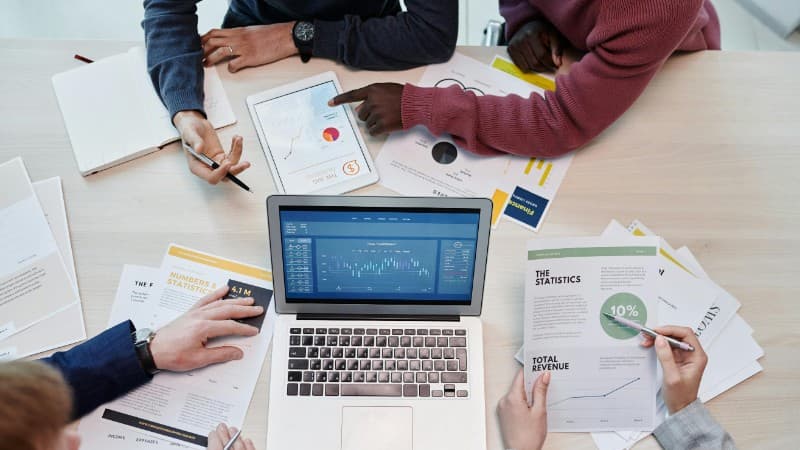 Top view of colleagues analyzing data on a digital device in an office setting., tags: casino affiliate tools roi - pexel