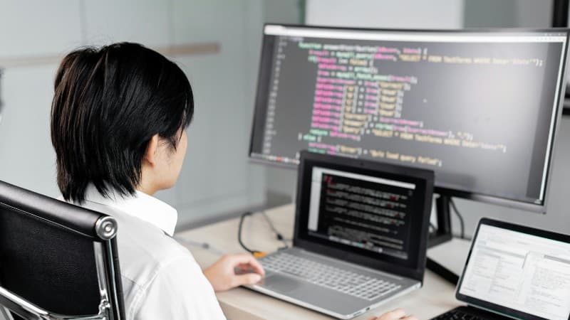 A software developer working on code with multiple screens in a modern office setting., tags: businesses casino affiliate - pexel